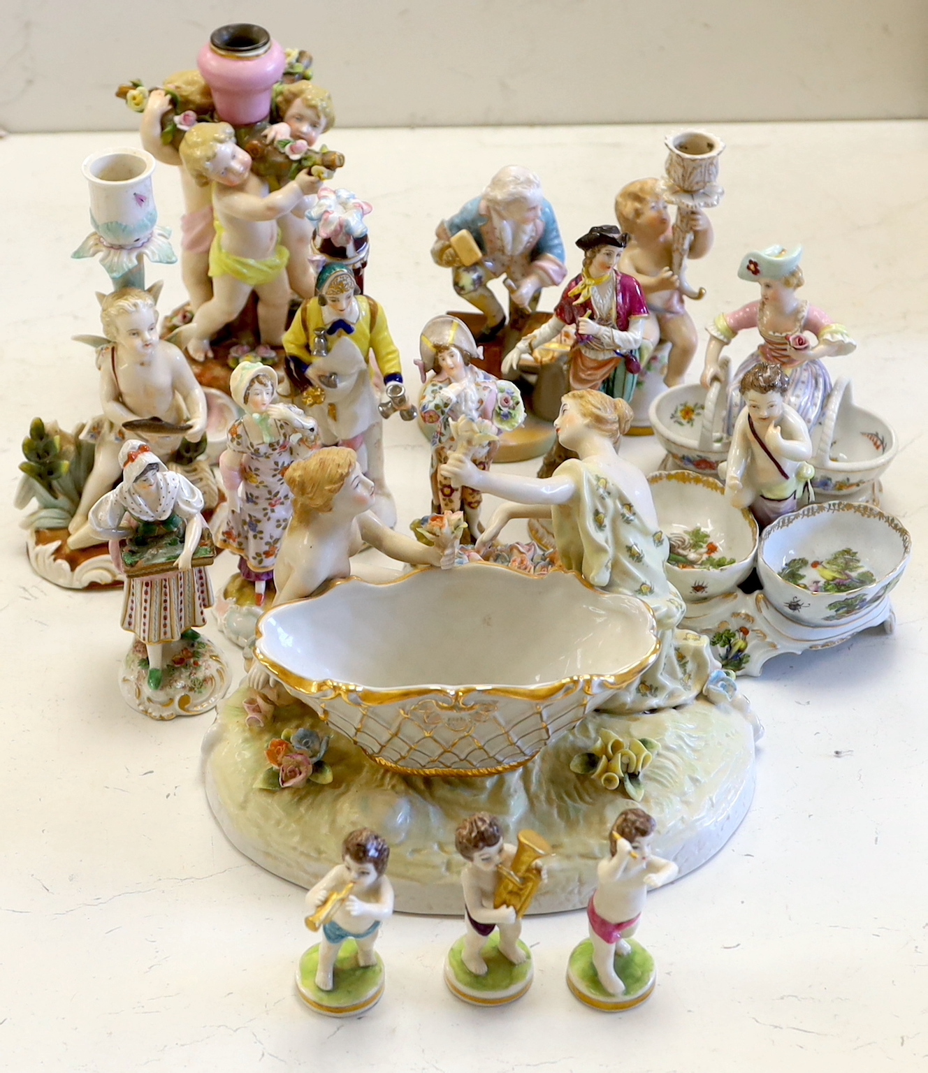 A collection of Continental porcelain figures, candleholders, table centres, some marked ‘AR’, cherubs, lovers, salesmen, tallest 20.5cm (15)